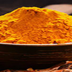 Composition with bowl of turmeric powder on wooden table